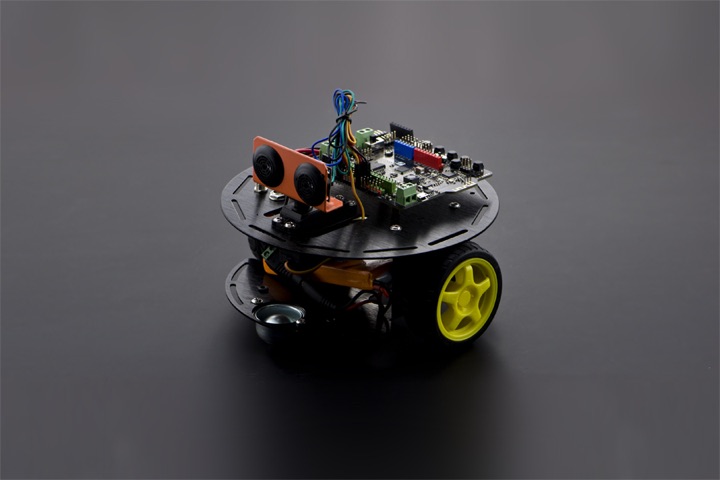 DFRobot Turtle 2WD Arduino robot kit with a round two-deck black chassis, yellow spoked wheels, front ultrasonic sensor, and exposed controller board on a dark background.