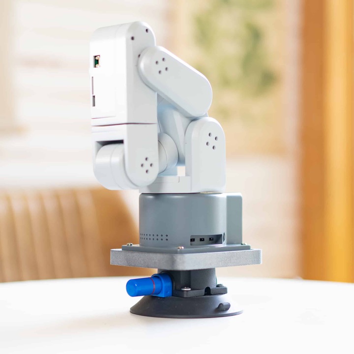 White and grey mechArm 270 six-axis robot arm mounted on a suction base on a round white table.