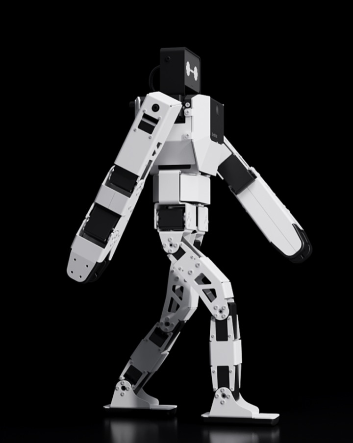 Side profile of the white-and-black Z-Bot humanoid robot mid-stride against a black background, with a rectangular display head and articulated arms and legs.